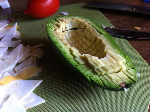 Een avocado gesneden kleine blokjes met een bot mes, zodat de huid intact blijft 